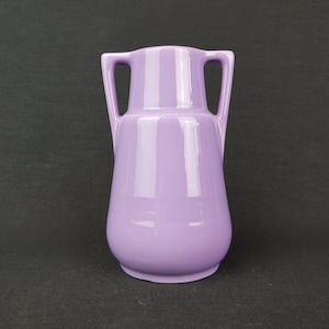 May include: A lavender ceramic vase with two handles. The vase has a smooth, glossy finish.