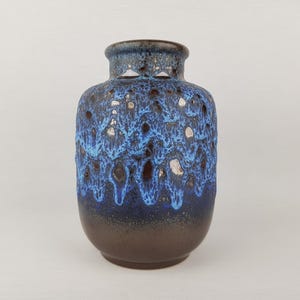 Peut inclure: Un vase en céramique bleu et brun avec un glaçage texturé unique. Le vase a un corps arrondi et une ouverture étroite.