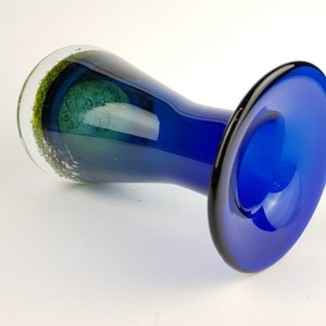 May include: A blue glass vase with a flared base and a green glass accent at the top.