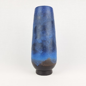 May include: A tall, blue and brown ceramic vase with a mottled glaze. The vase has a rounded base and a narrow neck.