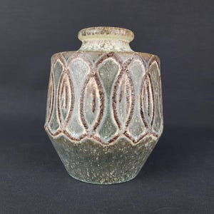 Może przedstawiać: Zielono-brązowy ceramiczny wazon z geometrycznym wzorem. Wazon ma zaokrąglone ciało i wąski otwór.
