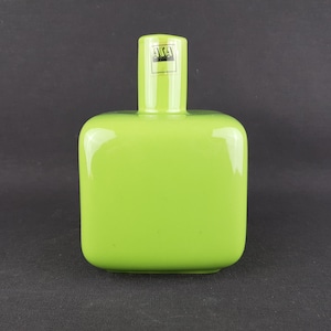 May include: A bright lime green ceramic vase with a square body and a short, cylindrical neck. The vase features a small, rectangular black and white label on the neck with the text ASA printed in a bold, sans-serif font on the front surface.