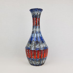 May include: A blue and red ceramic vase with a geometric pattern. The vase has a narrow neck and a wide base.