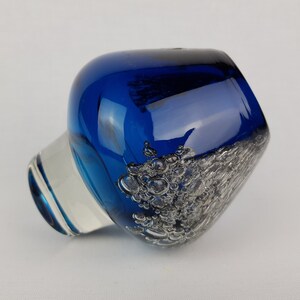 Puede incluir: Un jarr&oacute;n de vidrio azul cobalto con una base de vidrio transparente y una superficie texturizada. El jarr&oacute;n tiene una forma redondeada y una abertura ancha.