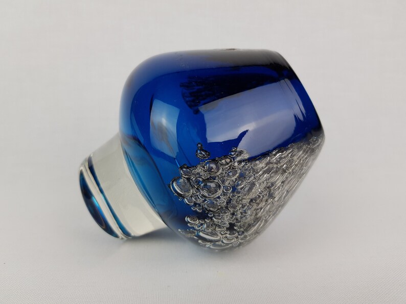 Puede incluir: Un jarr&oacute;n de vidrio azul cobalto con una base de vidrio transparente y una superficie texturizada. El jarr&oacute;n tiene una forma redondeada y una abertura ancha.