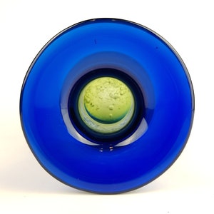 May include: A blue glass vase with a green glass interior. The vase has a wide mouth and a narrow base.