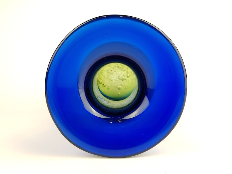 May include: A blue glass vase with a green glass interior. The vase has a wide mouth and a narrow base.