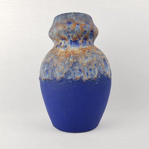 May include: A ceramic vase with a blue base and a textured, multi-toned top. The top section features shades of blue, brown, and white, creating a unique, artistic appearance. The vase has a rounded body and a slightly flared neck.
