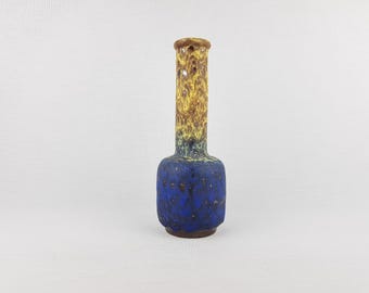 May include: A ceramic vase with a textured surface. The base is a deep blue, transitioning to yellow and brown at the top. The neck has several holes. A decorative piece for the home.