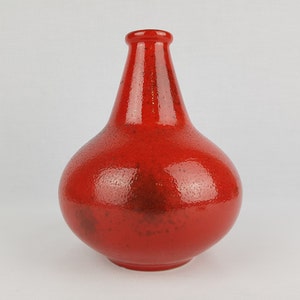 Könnte beinhalten: Eine rote Keramikvase mit strukturierter Oberfläche. Die Vase hat einen runden Körper und einen schmalen Hals.