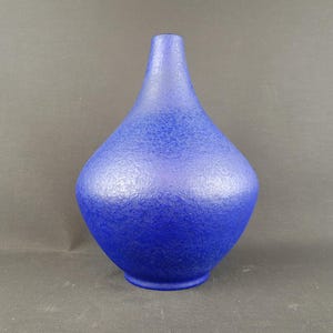 May include: A cobalt blue vase with a textured surface. The vase has a rounded base that tapers to a narrow neck. The vase is approximately 10 inches tall.