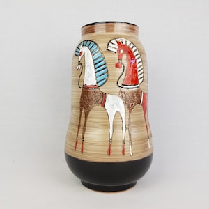 Może przedstawiać: Ceramiczny wazon z brązową i czarną podstawą i beżowym korpusem. Wazon jest ozdobiony dwoma końmi w stylizowanym wzorze, jeden z niebiesko-białą grzywą, a drugi z czerwoną grzywą.
