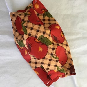 May include: A reusable face mask with a brown and white checkered pattern and red apples.