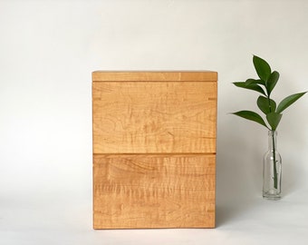Simple and elegant wooden urn with nesting keepsake tray. Made of flamed maple with birch and black walnut accents.