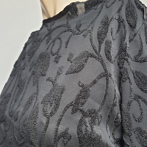 May include: Black long-sleeved shirt with a floral pattern. The pattern is raised and textured, giving the shirt a 3D effect.