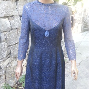 May include: A blue lace dress with a black bodice and a floral pattern. The dress has long sleeves and a round neckline.