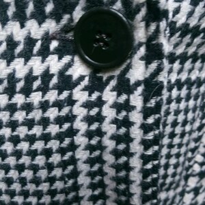 May include: A black and white houndstooth patterned fabric with a black button.