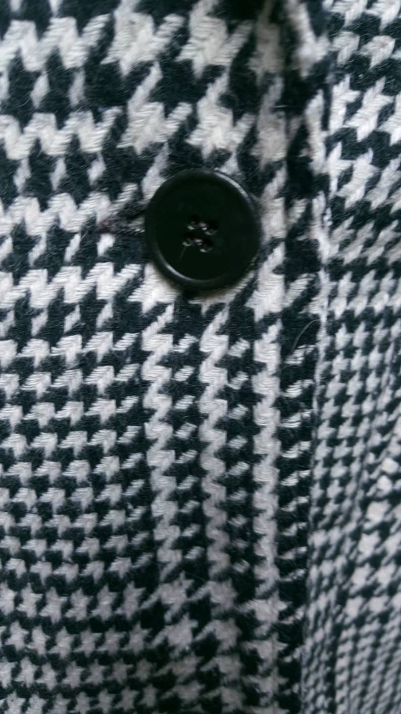May include: A black and white houndstooth patterned fabric with a black button.