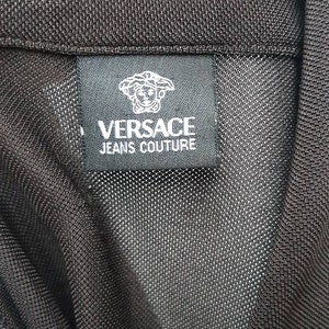 May include: Black label with white text that reads "VERSACE JEANS COUTURE" and a black and white logo of a woman's face with a crown.