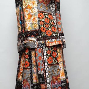 May include: A vintage-style dress with a patchwork design featuring orange, black and white floral patterns. The dress has a short-sleeved top and a skirt with a scalloped hem.