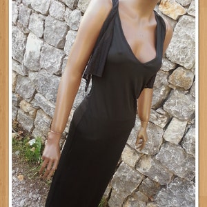 Puede incluir: Un vestido negro maxi con una superposición de encaje en los hombros. El vestido tiene un escote en V y una silueta ajustada.