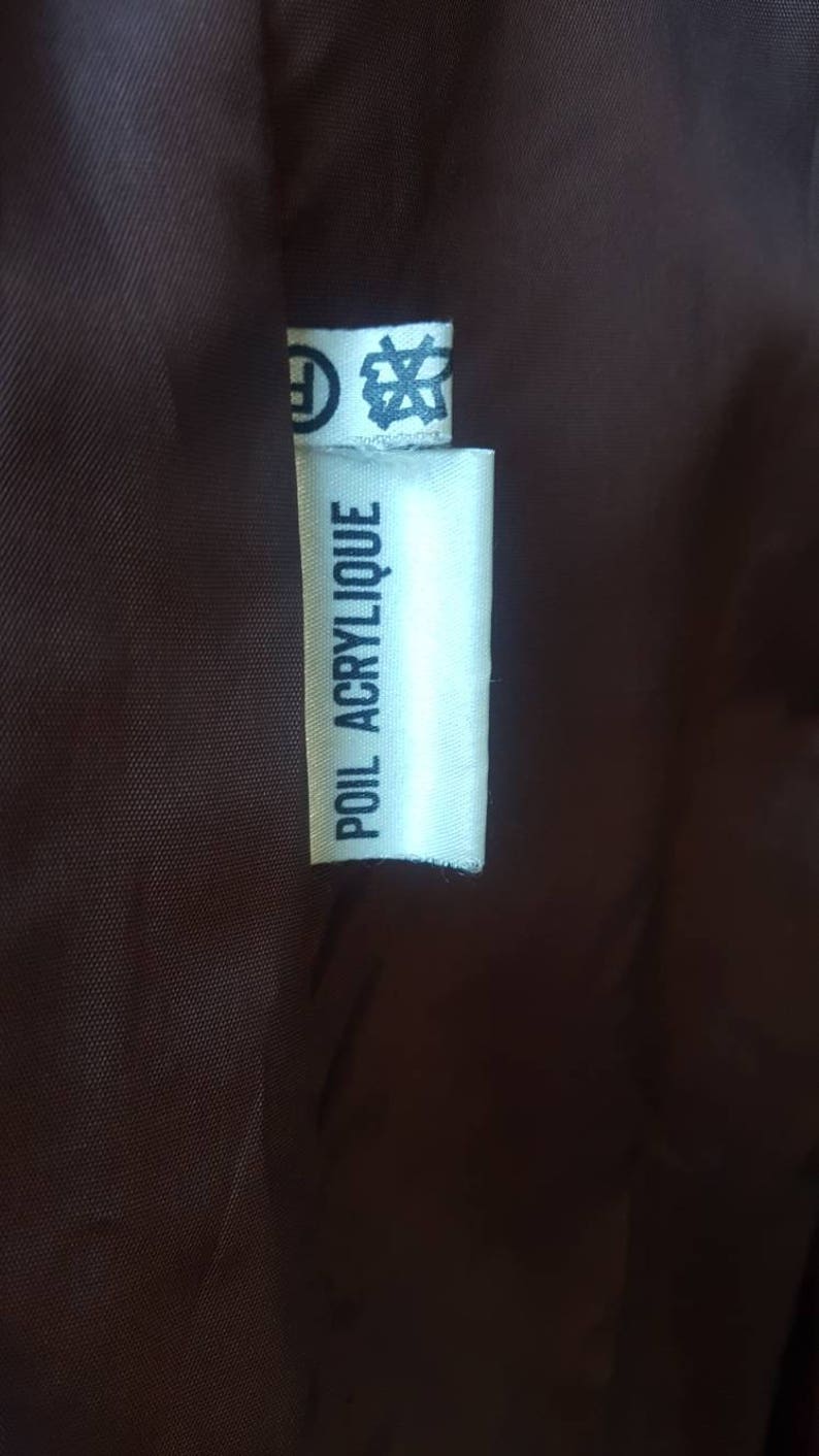May include: White fabric label with black text that reads "POIL ACRYLIIQUE".