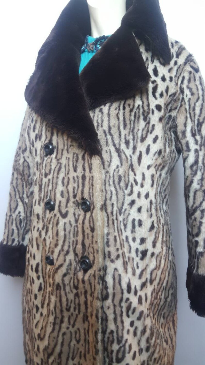 May include: A brown and white leopard print faux fur coat with a brown faux fur collar and cuffs. The coat has a double breasted closure with black buttons.