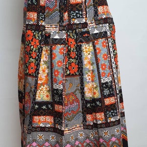 May include: A black midi skirt with a colourful patchwork design featuring orange, red and white flowers. The skirt has a geometric pattern at the hem.