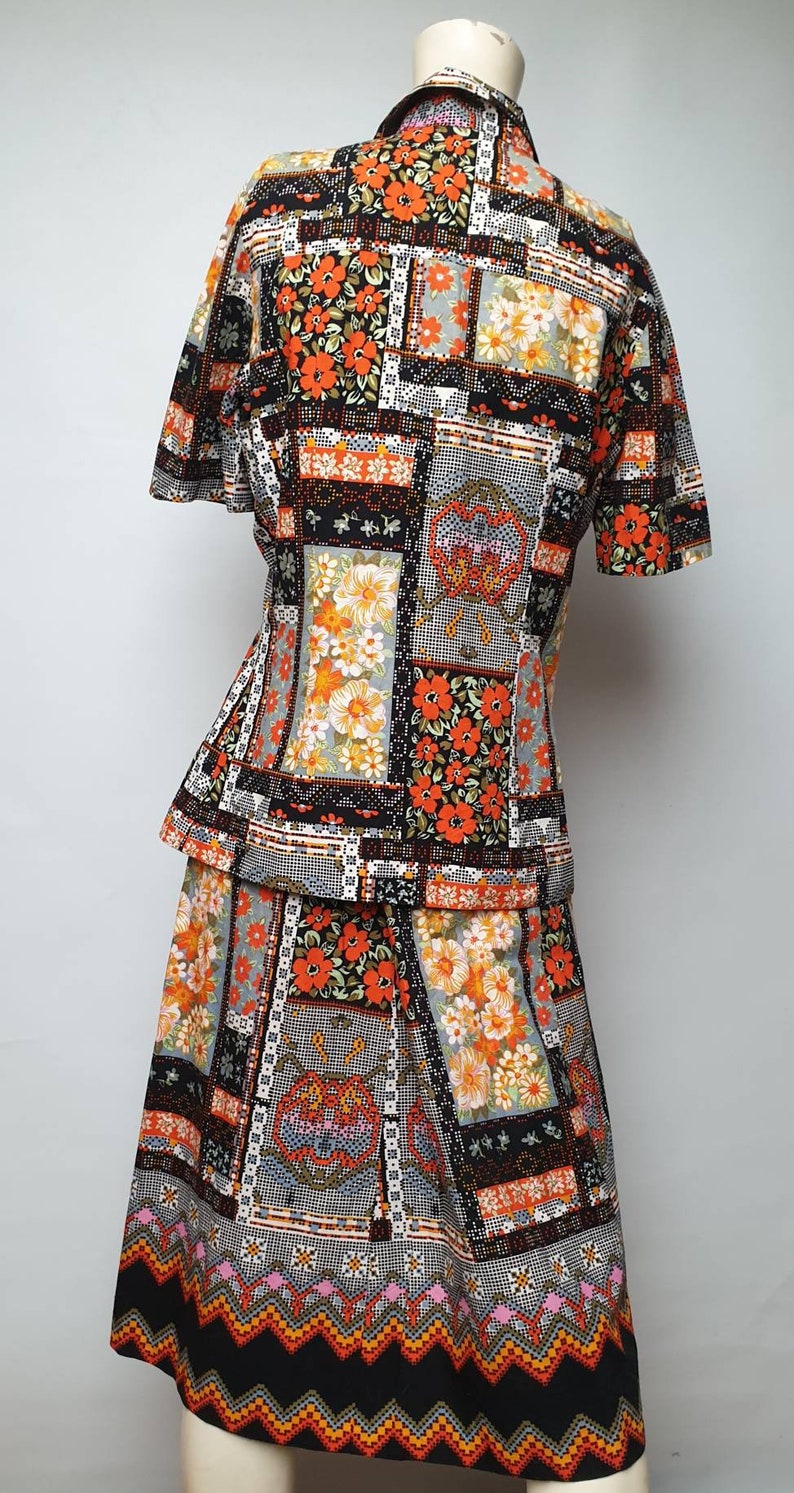 May include: A two-piece outfit consisting of a short-sleeved blouse and a skirt. Both pieces feature a patchwork design with orange, black and white floral patterns.