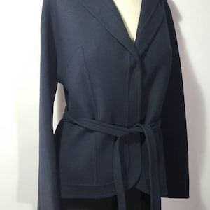 Op de afbeelding: Een donkerblauw getailleerd jasje met lange mouwen en een kraag.