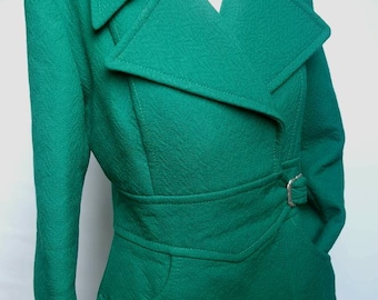 May include: A long-sleeved, emerald green coat with a large, pointed collar and a belt. The coat has a single pocket on the left side and a silver buckle on the belt.