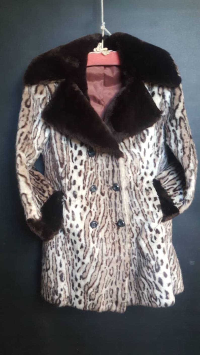 May include: A brown and white leopard print faux fur coat with a brown faux fur collar and cuffs. The coat has a double breasted closure with black buttons.