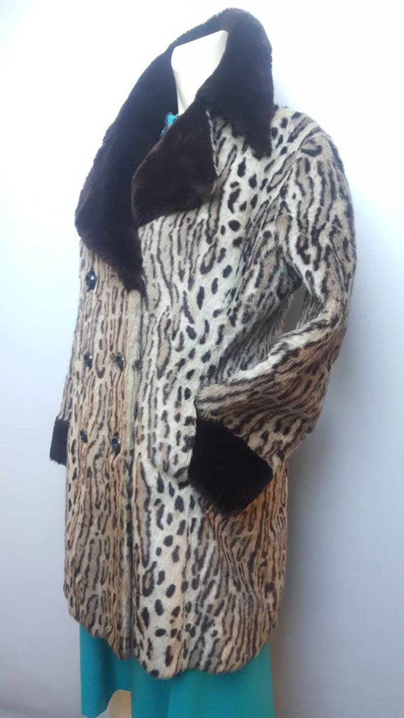 May include: A brown and tan leopard print fur coat with a brown fur collar and cuffs. The coat has a double breasted closure with black buttons.