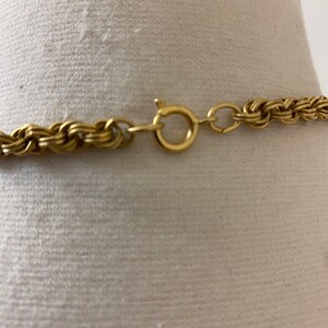 May include: A gold chain necklace with a braided design and a lobster clasp closure.