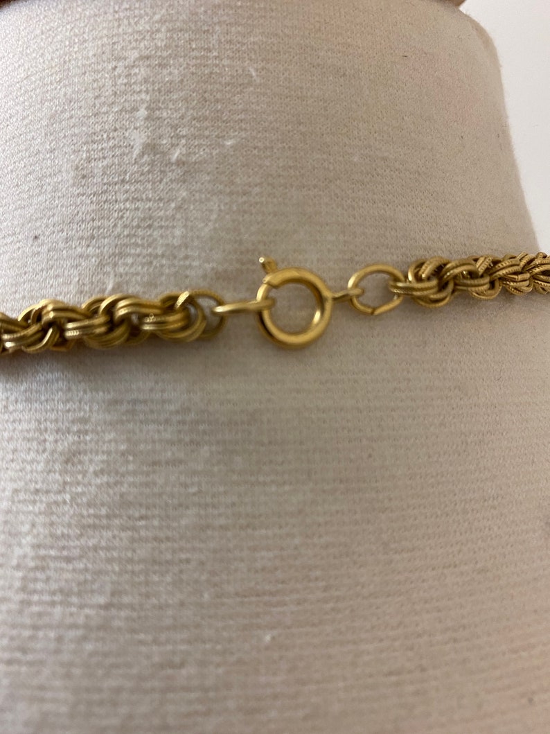 May include: A gold chain necklace with a braided design and a lobster clasp closure.
