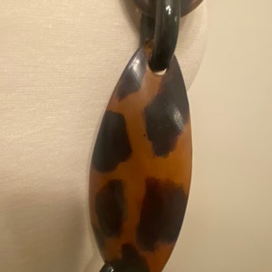 Peut inclure: Un collier &agrave; gros maillons ovales de couleur marron et noir. Le collier est en plastique et a une finition brillante.