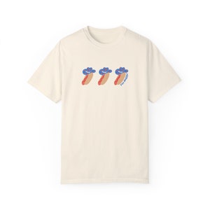 an ivory t-shirt with a graphic 3 hot dogs with red, white, and blue cowboy hats