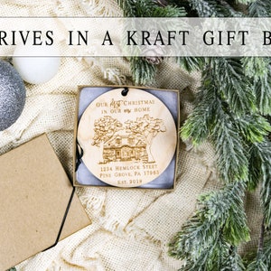 May include: A wooden Christmas ornament with the text "Our 1st Christmas in our new home" and the address "1234 Hemlock Street, Pine Grove, PA 17963, Est. 2019". The ornament is in a kraft gift box with a black ribbon.