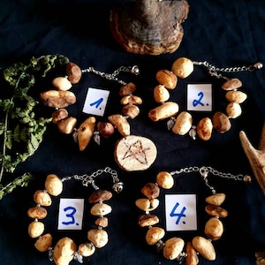 May include: Four bracelets made of natural wood beads with silver accents and charms. Each bracelet has a number from 1 to 4 written on a white tag.