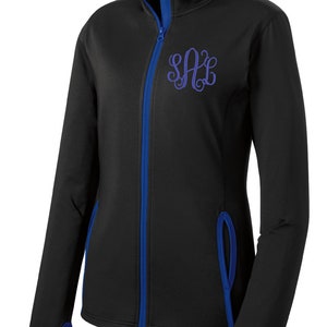 May include: Black zip-up jacket with blue trim and a purple monogram "SAC" embroidered on the chest.