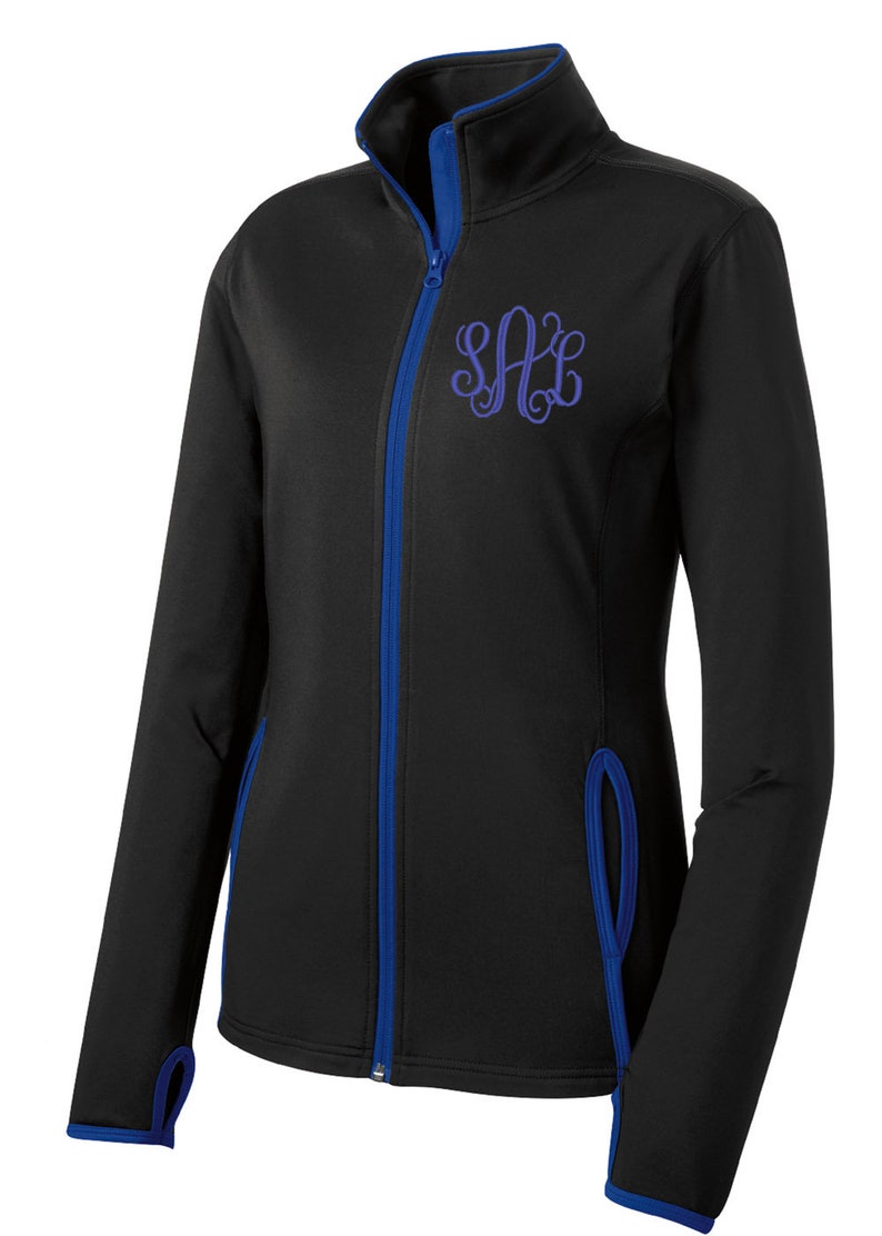 May include: Black zip-up jacket with blue trim and a purple monogram "SAC" embroidered on the chest.