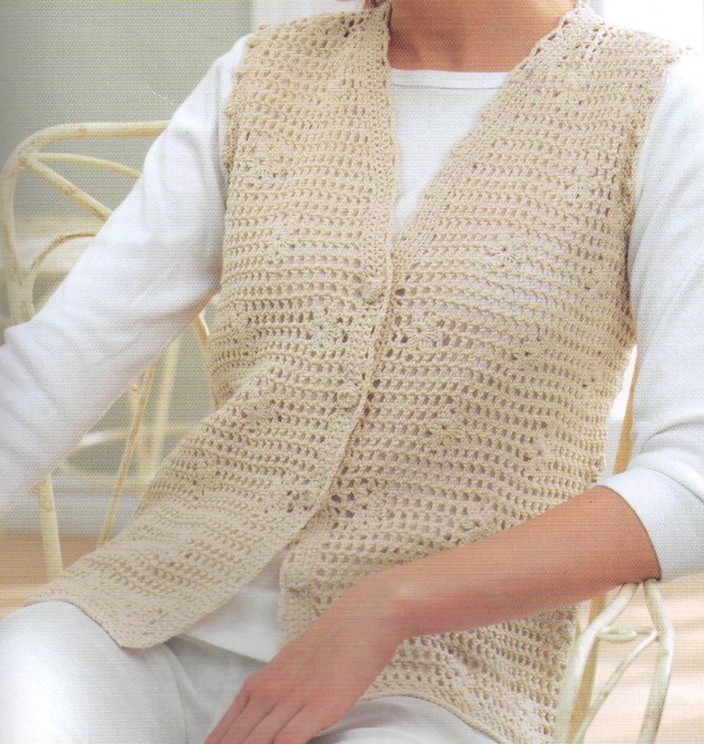May include: A crocheted vest with a button closure. The vest is made with a beige yarn and has a loose, open weave.