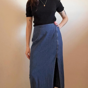 May include: A dark blue denim skirt with a front slit and a black mock neck shirt.