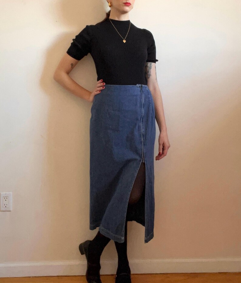 May include: A blue denim skirt with a front slit and a black mock neck shirt.