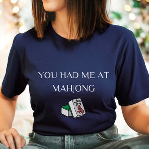 May include: A navy blue t-shirt with the text "You had me at Mahjong" and a graphic of two mahjong tiles.