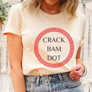 May include: A cream colored t-shirt with a red circle and the text "CRACK BAM DOT" inside the circle.