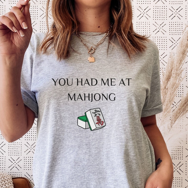 May include: Gray t-shirt with the text "You had me at Mahjong" and a graphic of mahjong tiles.