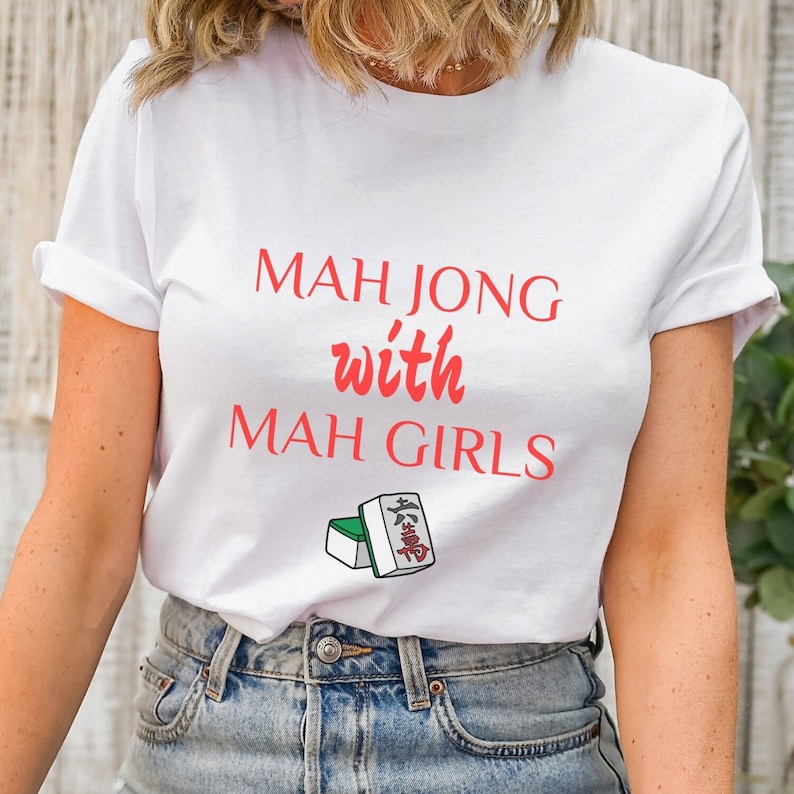 May include: White t-shirt with the text "Mah Jong with Mah Girls" in red. A small image of two mahjong tiles is below the text.