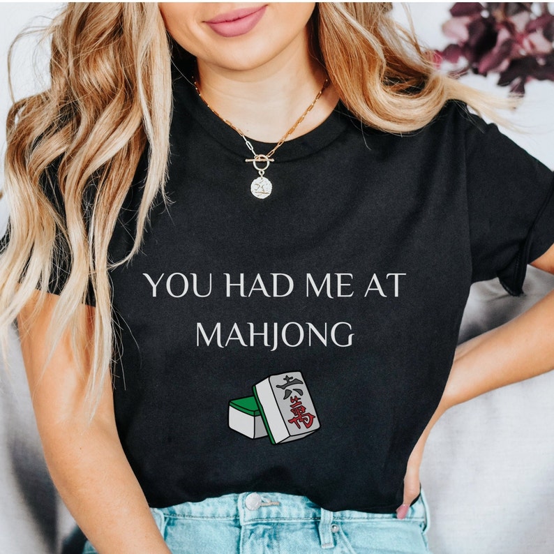 May include: Black t-shirt with the text "You had me at Mahjong" and a graphic of two mahjong tiles.