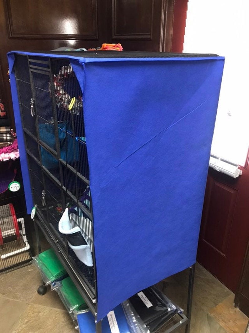 May include: A blue fabric cage cover for a large bird cage. The cage is made of metal and has multiple levels. The cover is made of a soft, blue fabric and has a black trim.